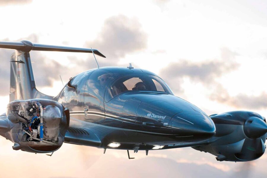 Diamond DA62 twin-engine aircraft in blue with exposed engine cowling in flight.