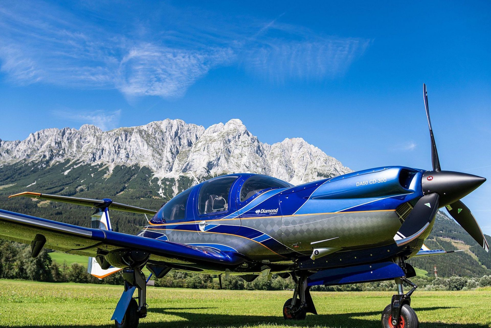 Diamond DA50 RG blue aircraft with retractable gear on grass airfield.