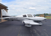 A white and grey single-engine propeller plane, registration number N603DG, parked on an asphalt tarmac in front of an open hangar.