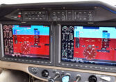 A close-up of a modern aircraft cockpit, featuring a "glass panel" with two large Garmin display screens showing flight instruments and navigation data.
