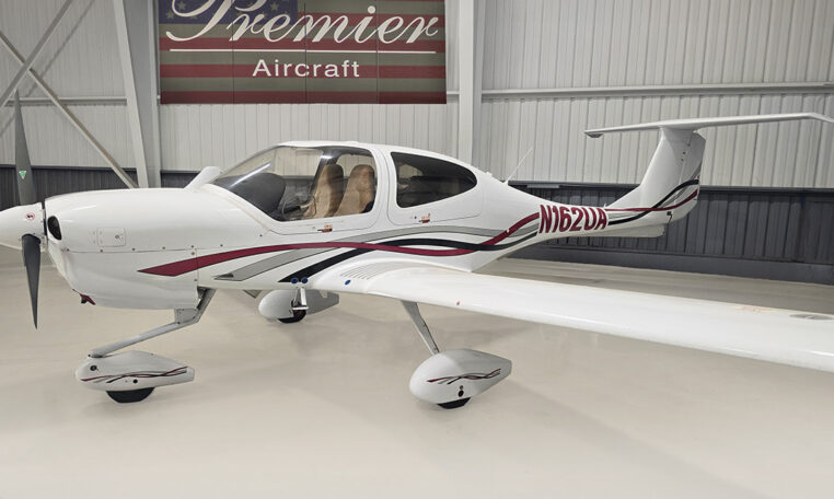 White single-engine propeller plane with T-tail in hangar at Premier Aircraft, registration N162UA.