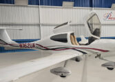 Diamond DA20 single-engine trainer aircraft in hangar with open canopy, tail number N162UA