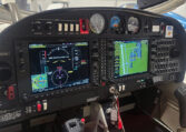 Modern general aviation cockpit with Garmin glass avionics, dual displays and controls in a hangar.