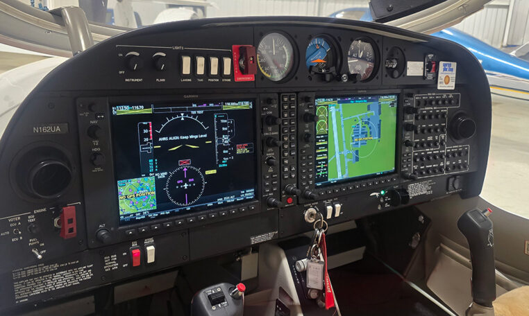 Modern general aviation cockpit with Garmin glass avionics, dual displays and controls in a hangar.