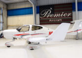Single‑engine low‑wing propeller plane in Premier Aircraft hangar, sleek white private aircraft on display