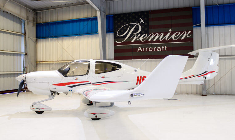 Single‑engine low‑wing propeller plane in Premier Aircraft hangar, sleek white private aircraft on display