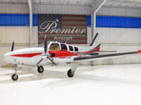 Red and white twin-engine propeller aircraft in a bright hangar at Premier Aircraft