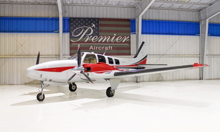 Red and white twin-engine propeller aircraft in a bright hangar at Premier Aircraft