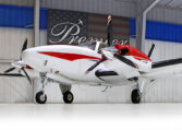 Red and white twin-engine propeller airplane in hangar at Premier, private aircraft for sale