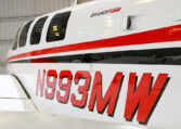 Beechcraft Baron G58 aircraft close-up showing red stripe and registration N993MW inside hangar.