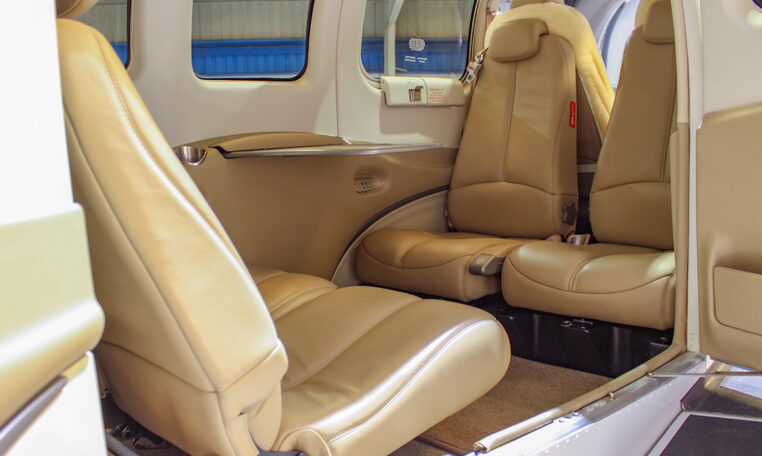 Private plane interior with tan leather seats and spacious cabin, view from open door, luxury air travel seating