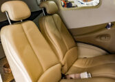 Tan leather passenger seats in a small private aircraft cabin, with headrests, seat belts and side window.