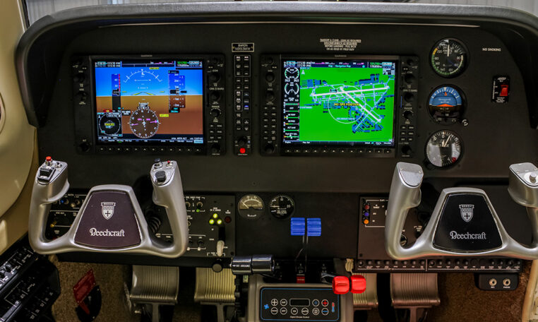 Beechcraft cockpit with Garmin G1000 dual displays, yokes, and avionics controls in a light twin-engine aircraft
