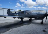 Dark gray single-engine propeller aircraft on airport tarmac near hangars, sleek T-tail design, tail number N41ZR.