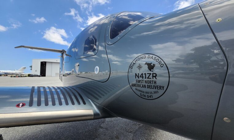 Diamond DA50 RG N41ZR first North American delivery badge on fuselage at airport ramp under blue sky