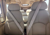 Private plane cabin interior with tan leather seats and seatbelts; rear bench visible at airport.