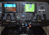 Light aircraft cockpit with dual Garmin G1000 displays, yokes and flight instruments on instrument panel.