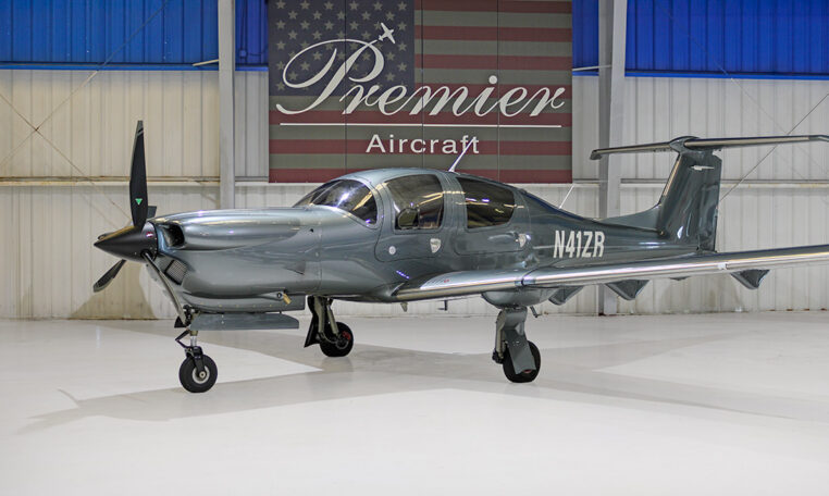 Sleek gray single-engine propeller plane in hangar at Premier Aircraft with American flag backdrop