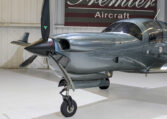 Modern metallic gray single-engine propeller aircraft in Premier Aircraft hangar, nose and landing gear close-up