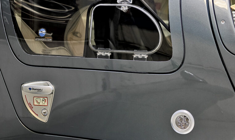 Diamond Aircraft airplane door close-up showing vent window, latch handle, and gray fuselage detail