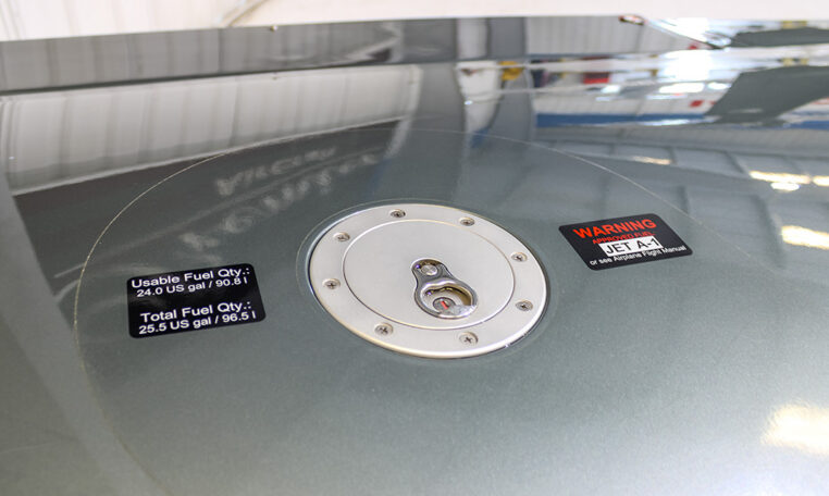Airplane wing fuel cap with Jet A-1 warning and labels: 24 gal usable, 25.5 gal total capacity, close-up in hangar.