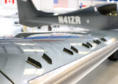 Close-up of aircraft wing vortex generators on a sleek private plane in a hangar, showcasing aerodynamic design details.