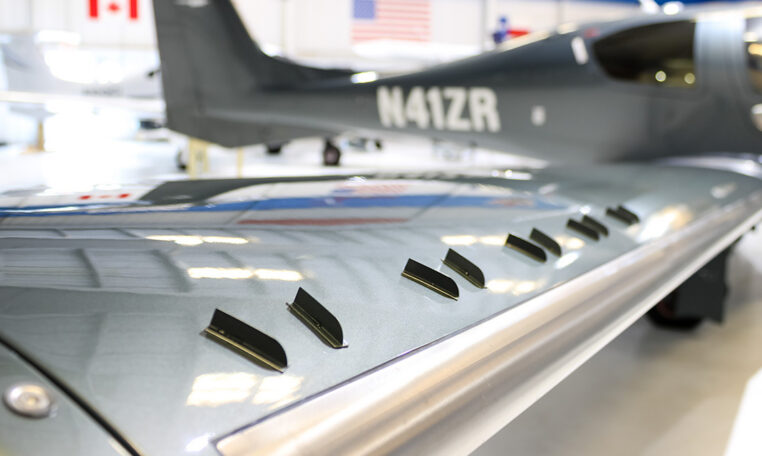 Close-up of aircraft wing vortex generators on a sleek private plane in a hangar, showcasing aerodynamic design details.