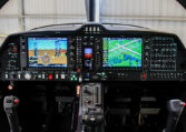 Light aircraft glass cockpit with Garmin G1000 dual displays, flight controls and instruments inside hangar