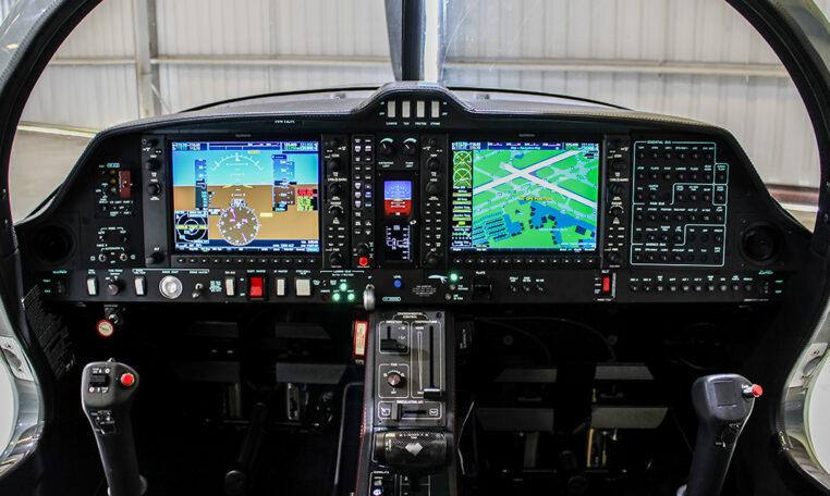Light aircraft glass cockpit with Garmin G1000 dual displays, flight controls and instruments inside hangar