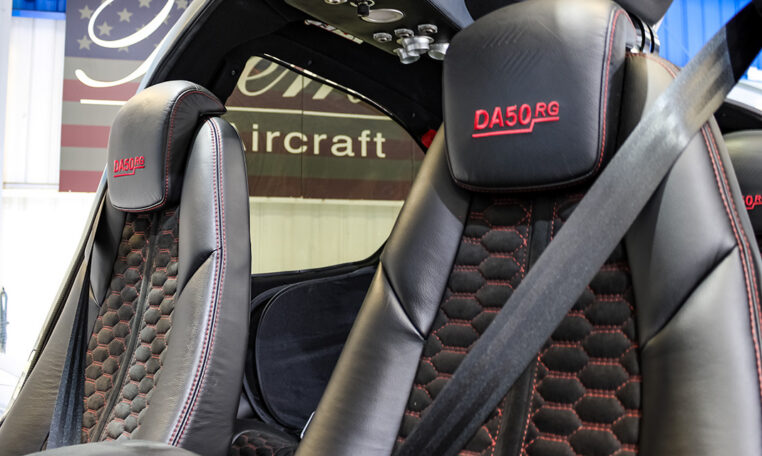 Diamond DA50 RG aircraft interior: black leather seats with red stitching and honeycomb pattern, cockpit seatbelt detail