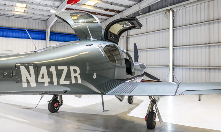 Single-engine piston airplane in hangar with gullwing doors open, N41ZR tail number visible, ready for private flight.