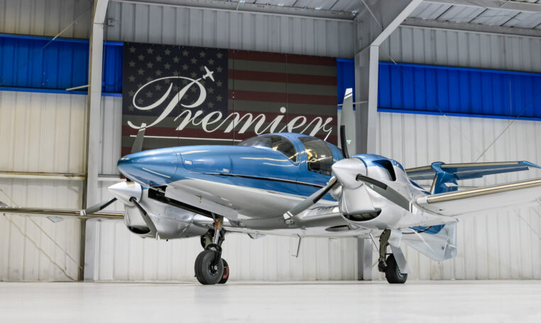 Sleek blue and silver twin-engine propeller aircraft in hangar at Premier, polished plane ready for sale or charter.