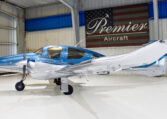 Blue and white twin-engine propeller plane parked in hangar at Premier Aircraft dealership