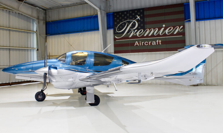 Blue and white twin-engine propeller plane parked in hangar at Premier Aircraft dealership