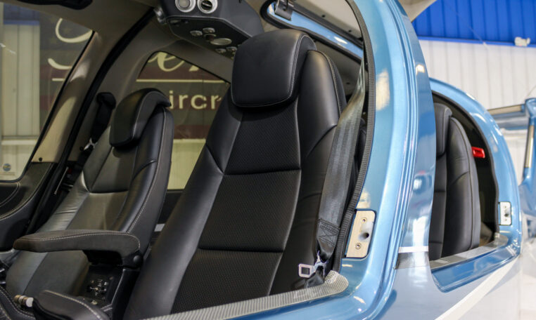Luxury helicopter interior with black leather seats and open door, showing cockpit armrest and modern trim.