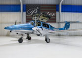 Blue and silver twin-engine propeller airplane in a hangar with gullwing doors open, private aircraft N895PA