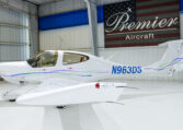 White low-wing single-engine aircraft N963DS in Premier Aircraft hangar, sleek design with tinted canopy.