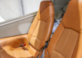 Private airplane interior with two tan leather seats and seat belts in a light aircraft cabin.