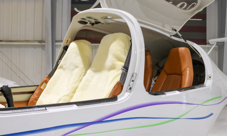 Diamond DA40 aircraft cockpit with sheepskin front seats, tan leather rear seats, open canopy in hangar