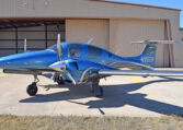 Blue twin-engine propeller aircraft parked outside an airport hangar, private plane ready for flight training or travel.