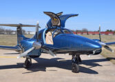 Sleek blue twin-engine propeller private plane with gullwing doors open on airport tarmac.