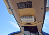 Diamond Aircraft cockpit overhead panel with AUX power controls and pilot checklist pocket, blue sky view.