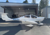 White single-engine propeller plane N963DS outside an open hangar at a small airport on a sunny day.