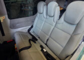 Private plane interior with light gray leather rear bench seats, seat belts, and clean cabin upholstery.