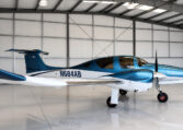 Blue and white single-engine propeller airplane parked in a clean aircraft hangar, tail number N684AB