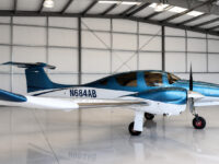 Blue and white single-engine propeller airplane parked in a clean aircraft hangar, tail number N684AB