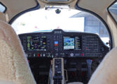 Diamond DA62 glass cockpit with Garmin G1000 NXi avionics and dual yokes, view from cabin seats in hangar.