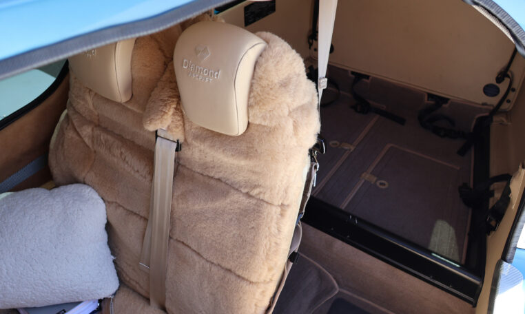 Diamond Aircraft interior with sheepskin rear seats and spacious luggage bay, beige upholstery and seatbelts.