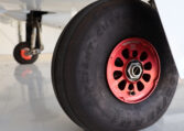 Aircraft landing gear close-up: Goodyear tire with red Beringer wheel hub in hangar.