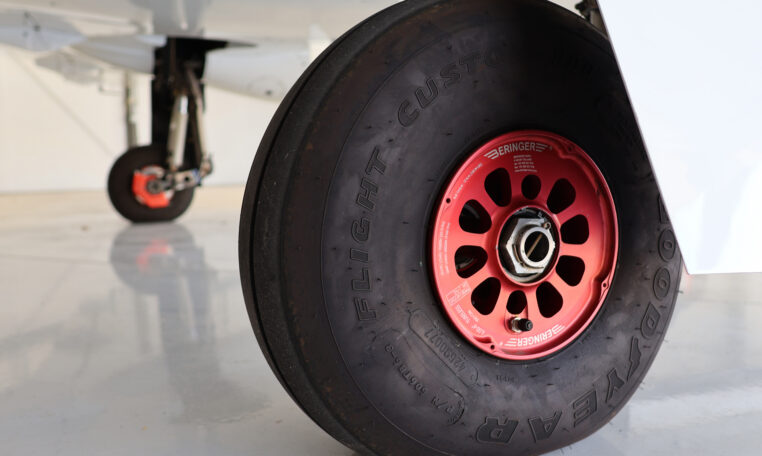 Aircraft landing gear close-up: Goodyear tire with red Beringer wheel hub in hangar.